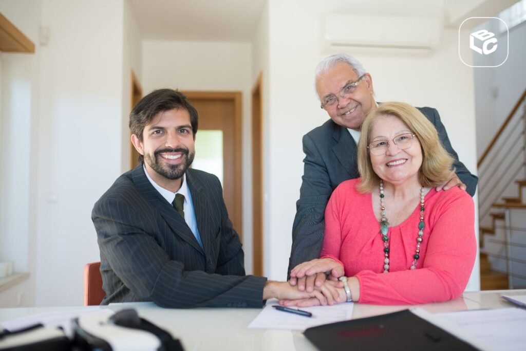 Advogado sorridente cumprimenta casal sênior em reunião de negócios.