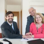 Advogado sorridente cumprimenta casal sênior em reunião de negócios.